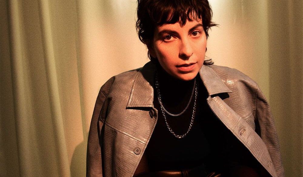 Photo of Becca Mancari looking at the camera with a coat over their shoulders