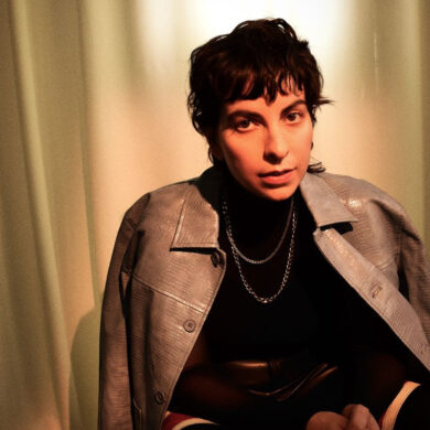 Photo of Becca Mancari looking at the camera with a coat over their shoulders