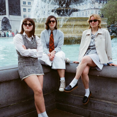 Girl Ray sitting on a wall wearing sunglasses.