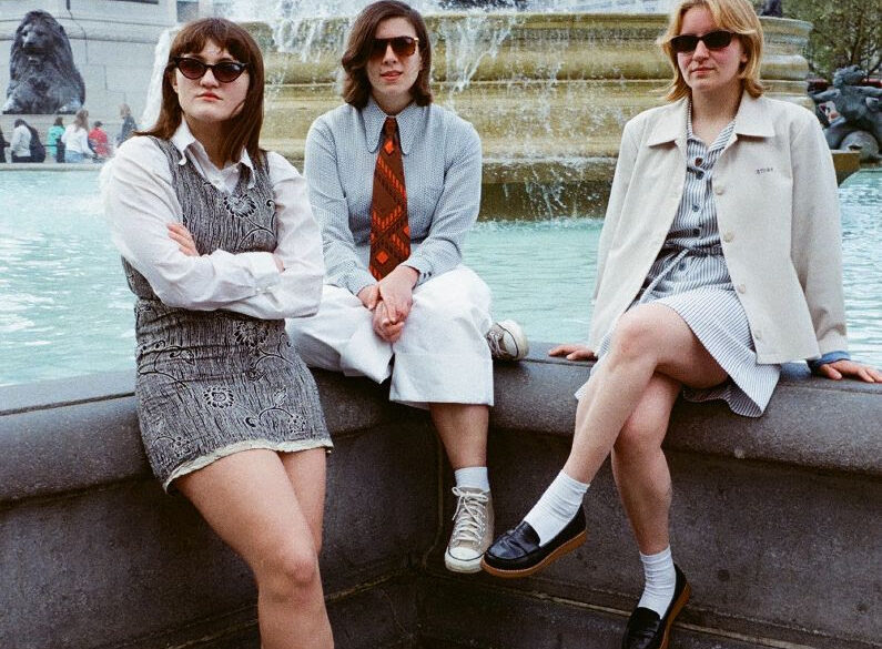 Girl Ray sitting on a wall wearing sunglasses.