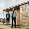 The band duo JOHN standing in front of a shed