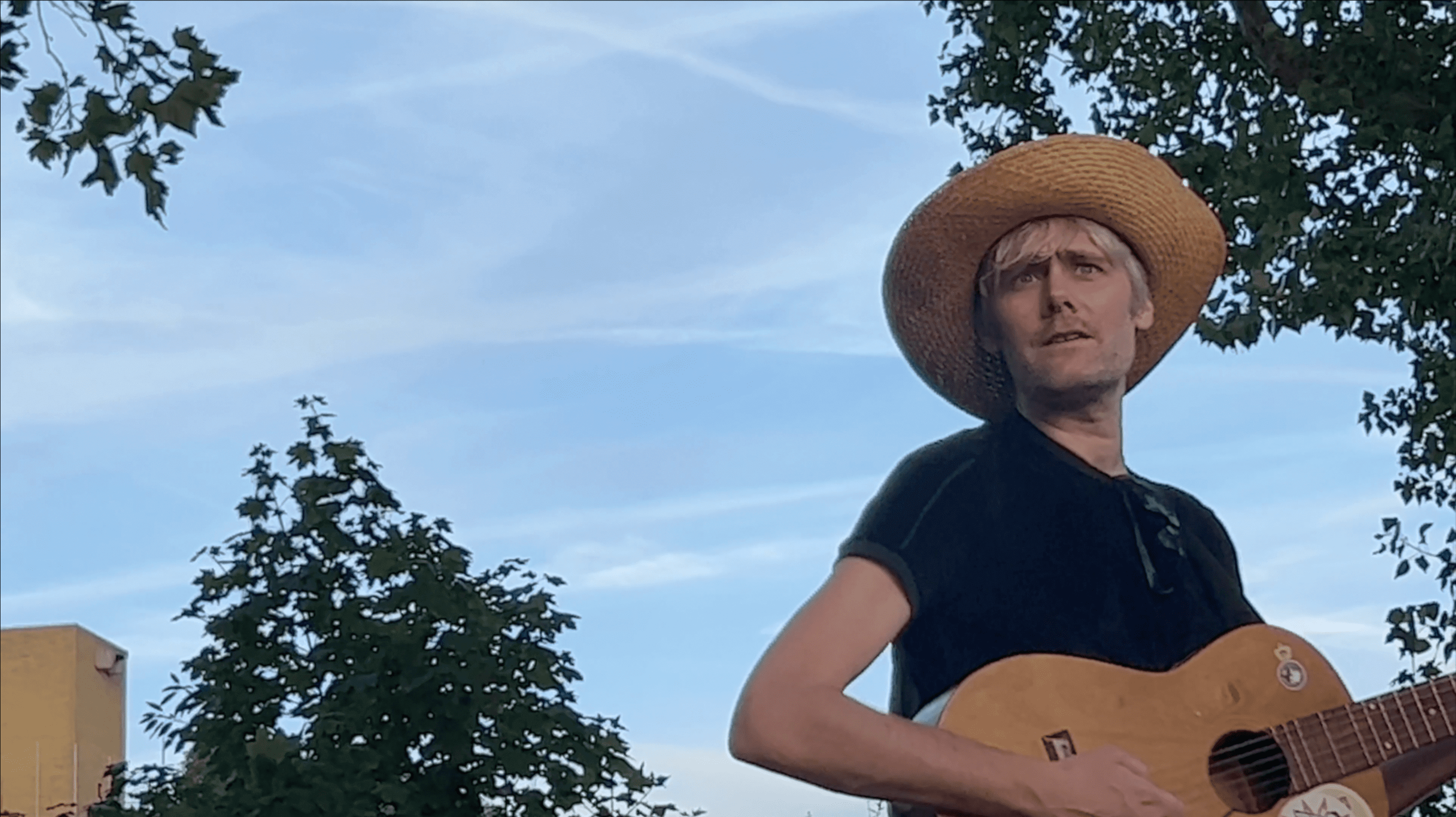 Alex Sebley from Pregoblin wearing a straw hat and holding a guitar.