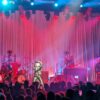 Photo of Lainey Wilson on stage with her band around her.