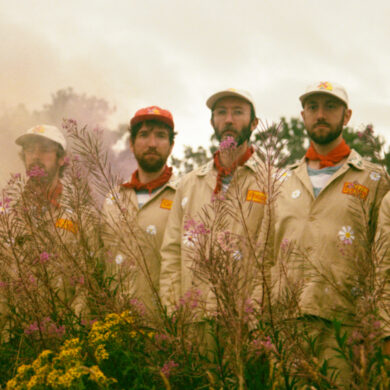 Six men in boiler suits standing in front of a mill.