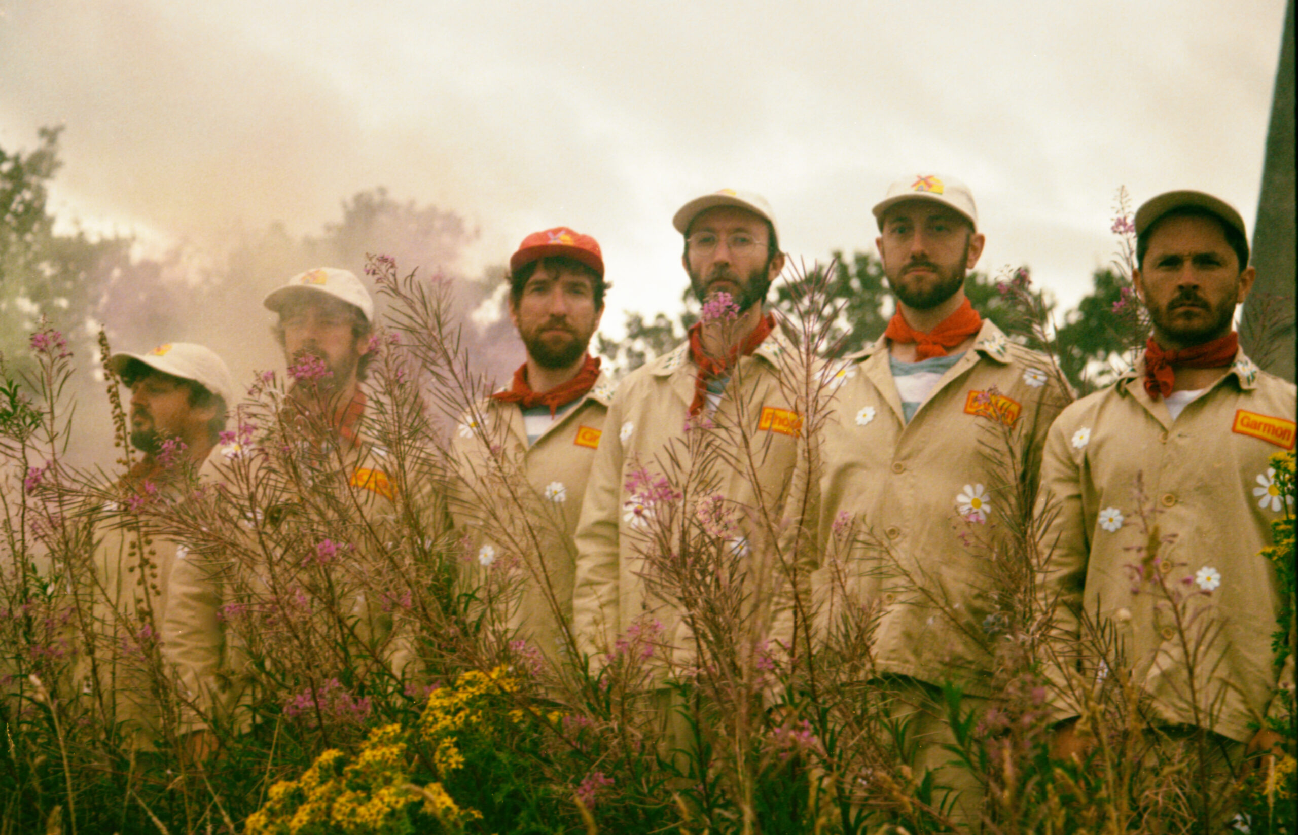 Six men in boiler suits standing in front of a mill.
