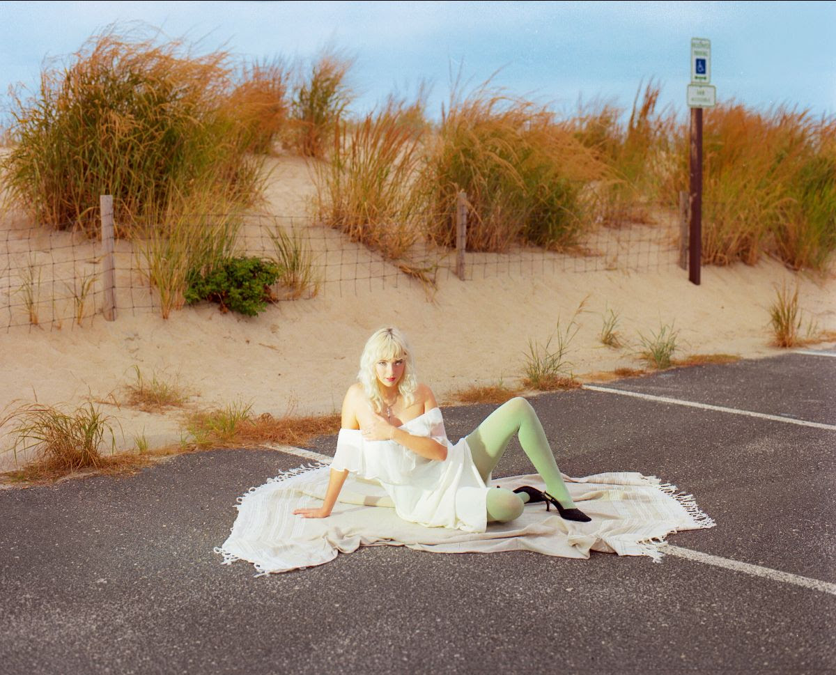 girlpuppy sitting on the floor in a car parking space by the beach